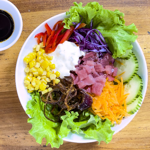 PalmBeach Tropical Restaurant | Tuna and Rice Poke | bowl of rice with raw tuna, corn, cucumbers, green salad, purple cabbage, fried onions, sesame seeds, mayonnaise and served with soy sauce on the side